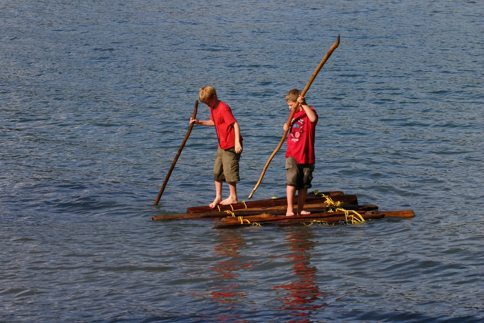 Two young men pole a raft they built across the lake, 2003