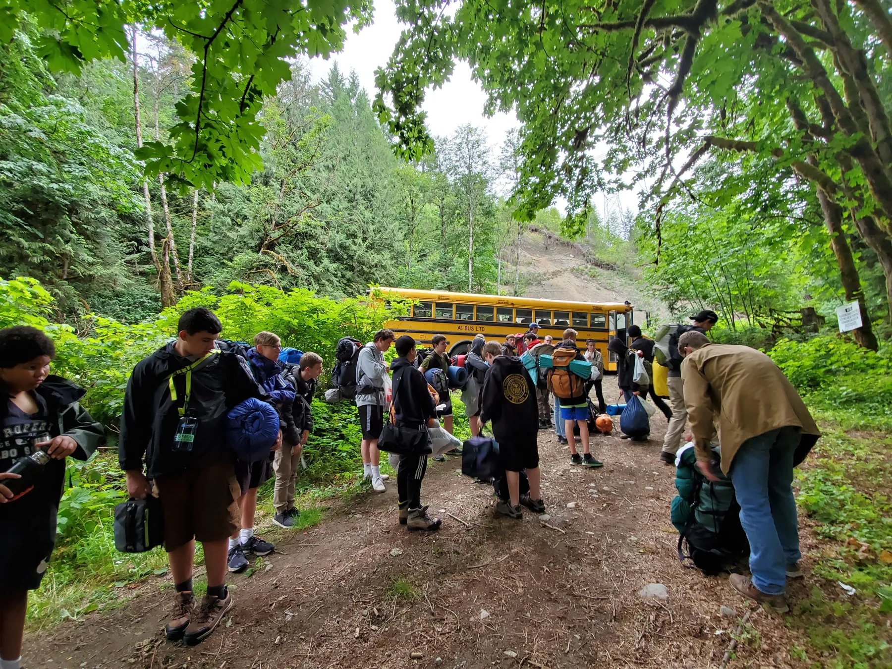 Young men shoulder their packs at the trailhead