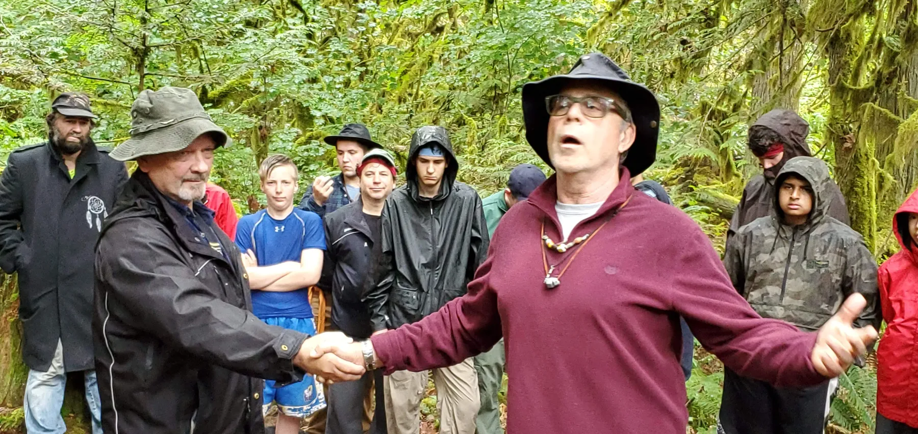 Men in the forest circle, arms out