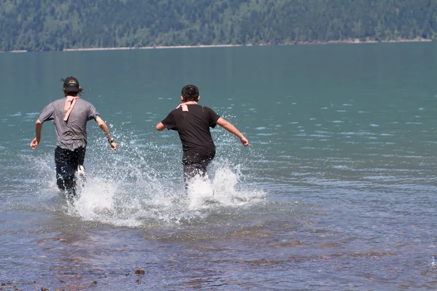 two young men running into the lake